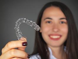 Mujer mostrando que tiene tratamiento con ortodoncia invisible 