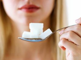 mujer con diabetes mirando una cuchara con azúcar