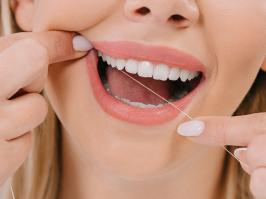 Mujer limpiando sus dientes con Seda Dental