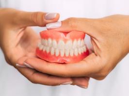 Manos sosteniendo unas prótesis dentales fijas  
