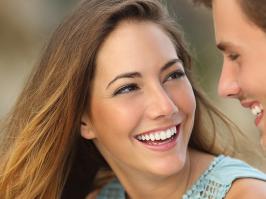 Mujer y hombre sonríen viéndose a los ojos