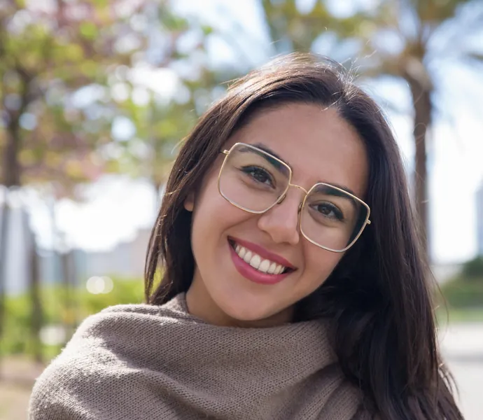 Mujer sonriendo con gafas gracias a su tratamiento de ortodoncia